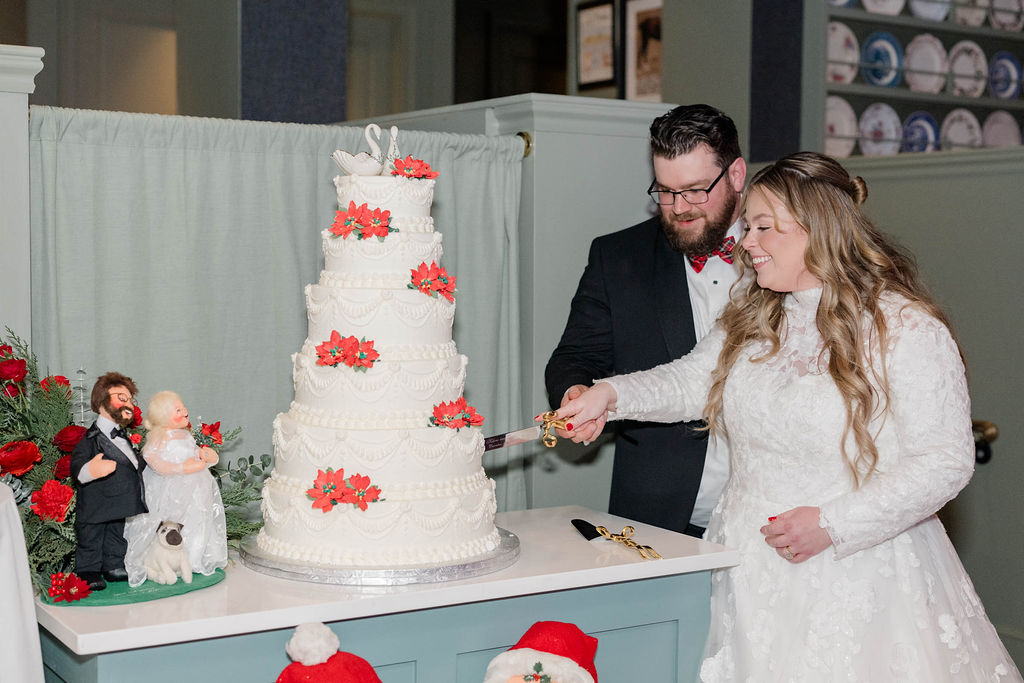 Helene & David Cutting Their Wedding Cake with Annalee design nearby